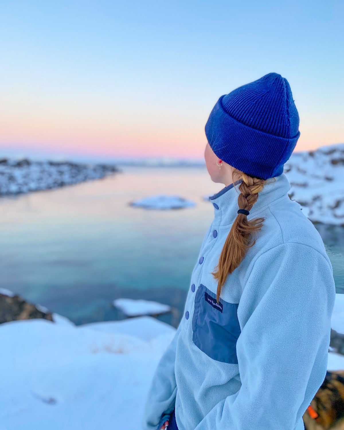 Fresh Powder Fleece – kvinne sett bakfra i fleecen ved en fjord i vintersolnedgang