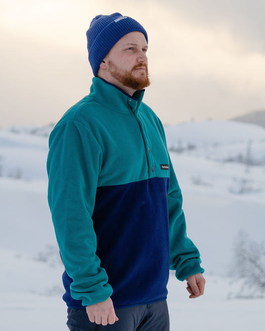 Polar Fleece – mann med blå lue i fleecen i snølandskap