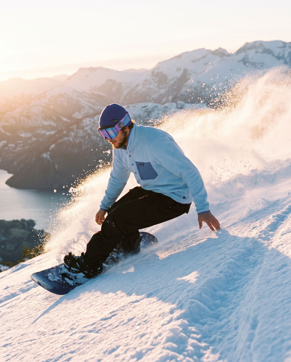 Fresh Powder Fleece – snowboarder carver i puddersnø over fjorden i solnedgang