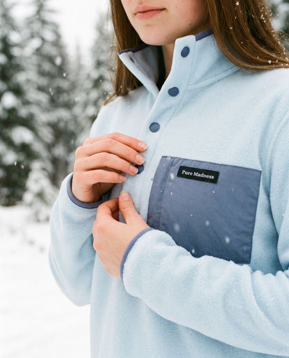 Fresh Powder Fleece – nærbilde av hender som knepper fleecen, med brystlomme og lapp