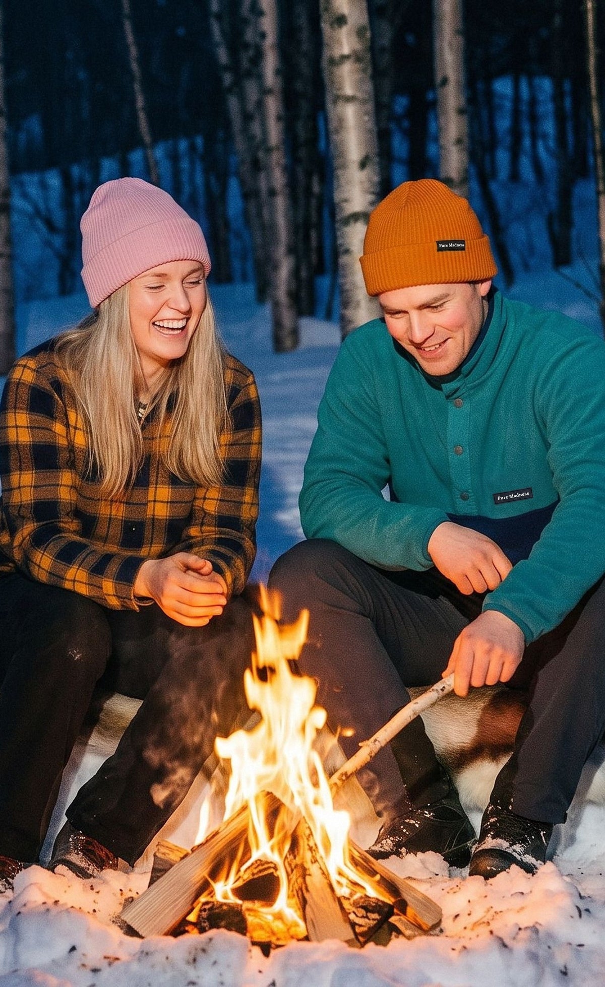 To venner ler rundt et bål i en snødekt bjørkeskog, i Pure Madness merinolue og fleece