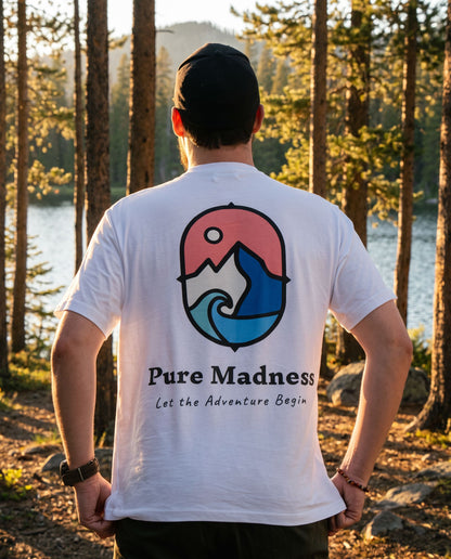Let the Adventure Begin White Tee – mann sett bakfra med trykket på ryggen i furuskog ved et vann