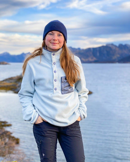 Fresh Powder Fleece – kvinne i lyseblå fleece med marineblå lue ved fjorden