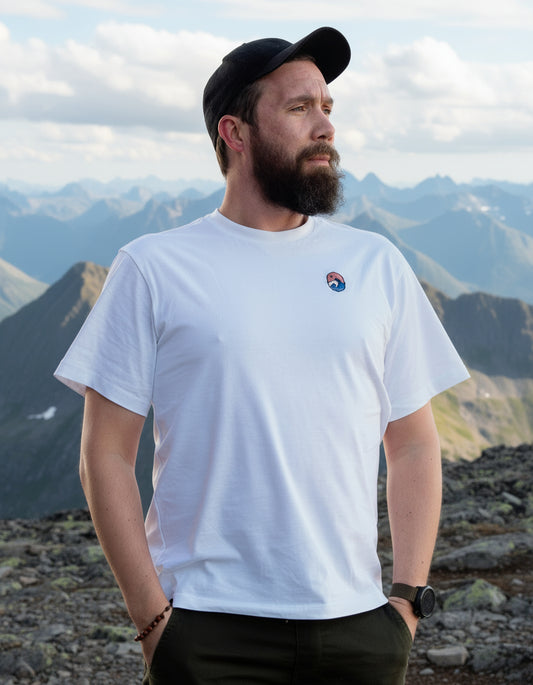 Let the Adventure Begin White Tee – mann med svart caps i hvit t-skjorte på en fjelltopp